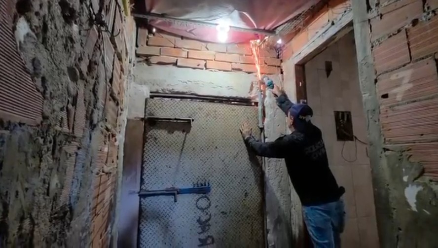 Um policial usa um maçarico para fazer a retirada da porta de ação do 'bunker' do tráfico